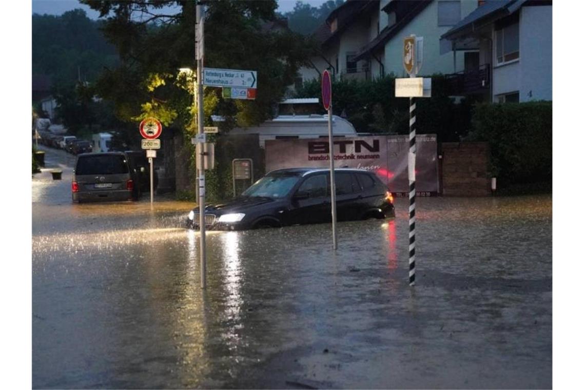 Ein Auto steht nach einem heftigen Unwetter auf einer Straße in Aichtal im Wasser. Foto: Sven Kohls/SDMG/dpa