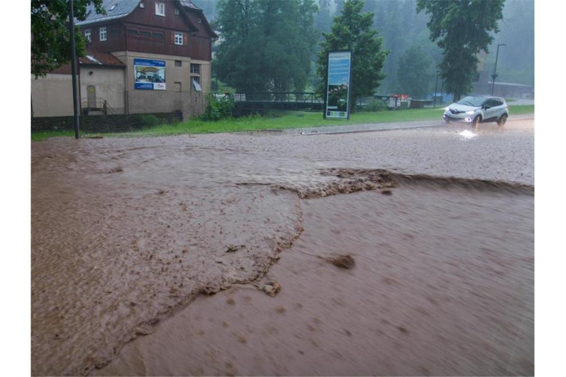 Ein Auto steht während eines heftigen Unwetters auf einer überfluteten Straße in Altensteig im Landkreis Calw. Foto: Aaron Klewer/Einsatz-Report24/dpa
