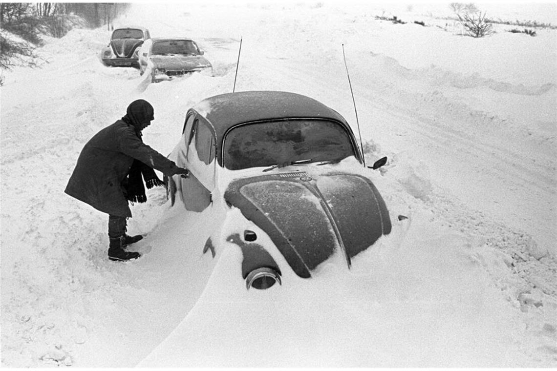 Ein Autofahrer steht in Cuxhaven neben seinem am Straßenrand im Schnee stecken gebliebenen VW-Käfer.