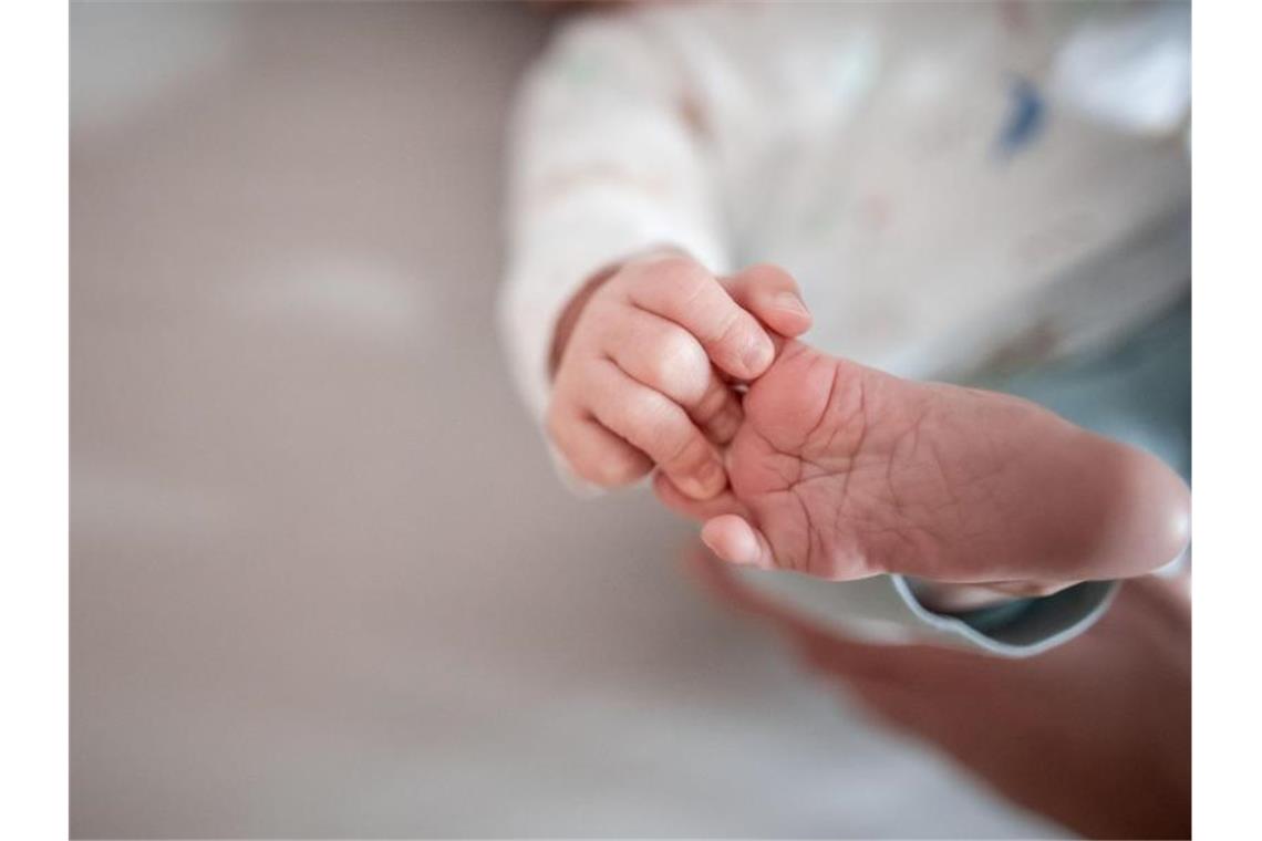 Ein Baby greift mit den Fingern nach seinem Fuß. Foto: Fabian Strauch/dpa/Symbolbild