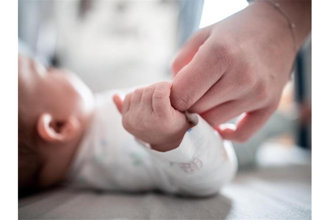 Ein Baby klammert sich an den Finger seiner Mutter. Frauen in Deutschland haben im Jahr 2019 weniger Babys auf die Welt gebracht als 2018. Foto: Fabian Strauch/dpa