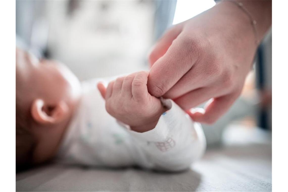 Ein Baby klammert sich an einen Finger seiner Mutter. (Archivbild). Foto: Fabian Strauch/dpa