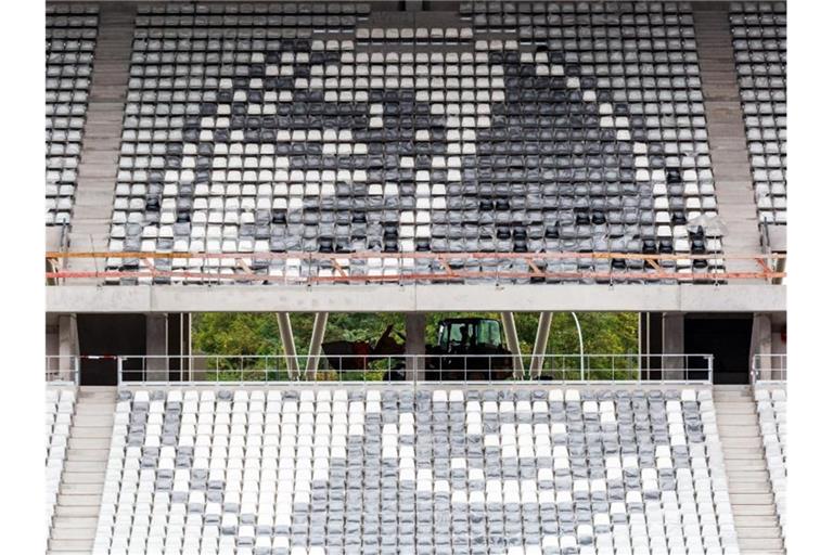 Ein Bagger fährt hinter dem aus Sitzschalen gebauten Logo des SC Freiburg über die Baustelle. Foto: Philipp von Ditfurth/dpa/archivbild