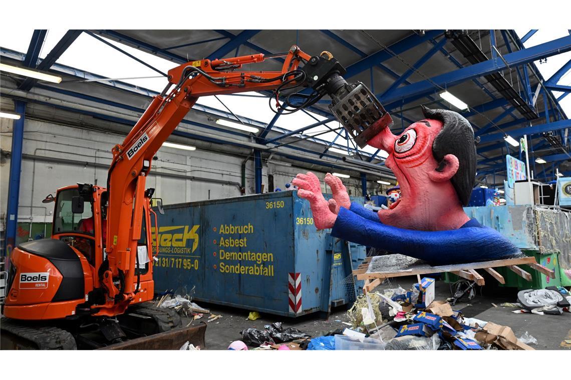 Ein Bagger hebt in Düsseldorf eine Pappfigur eines Rosenmontagszugs in den Müll. Nachdem die Motive zahlreiche Zuschauer begeisterten, werden sie abgerissen.
