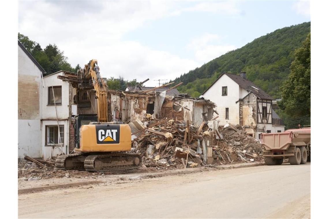 Ein Bagger reisst in Altenburg (Rheinland-Pfalz) Häuser ab, die durch die Flutkatastrophe zerstört wurden. Foto: Thomas Frey/dpa