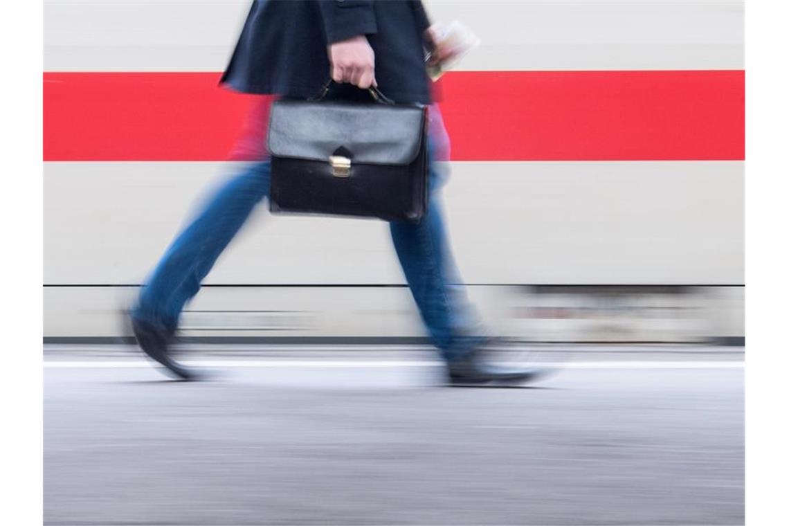 Arbeitgeber und DGB forden zusätzliche Reformen Ein Bahnpendler mit Aktenkoffer geht an einem Zug vorbei. Ein Jahr nach der Einigung der schwarz-roten Koalition auf ein milliardenschweres Konjunkturpaket gegen die Auswirkungen der Corona-Krise fordern Wirtschaft und Gewerkschaften zusätzliche Reformen. Foto: Sebastian Gollnow/dpa