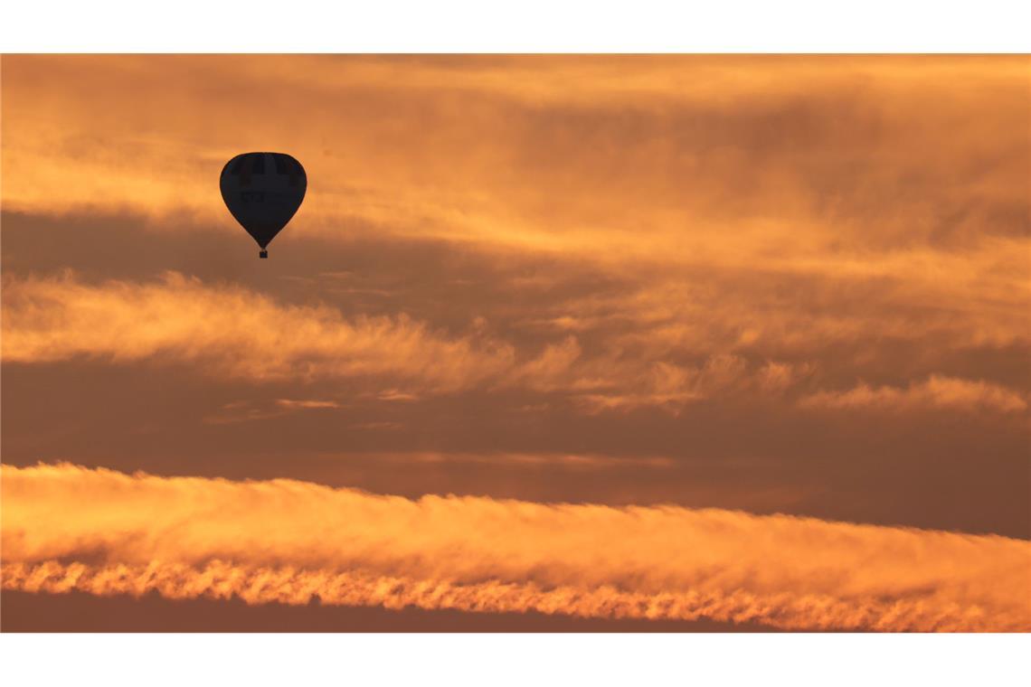 Bilder des Tages Ein Ballon ist am Morgen kurz vor Sonnenaufgang am orange gefärbten Morgenhimmel zu sehen.