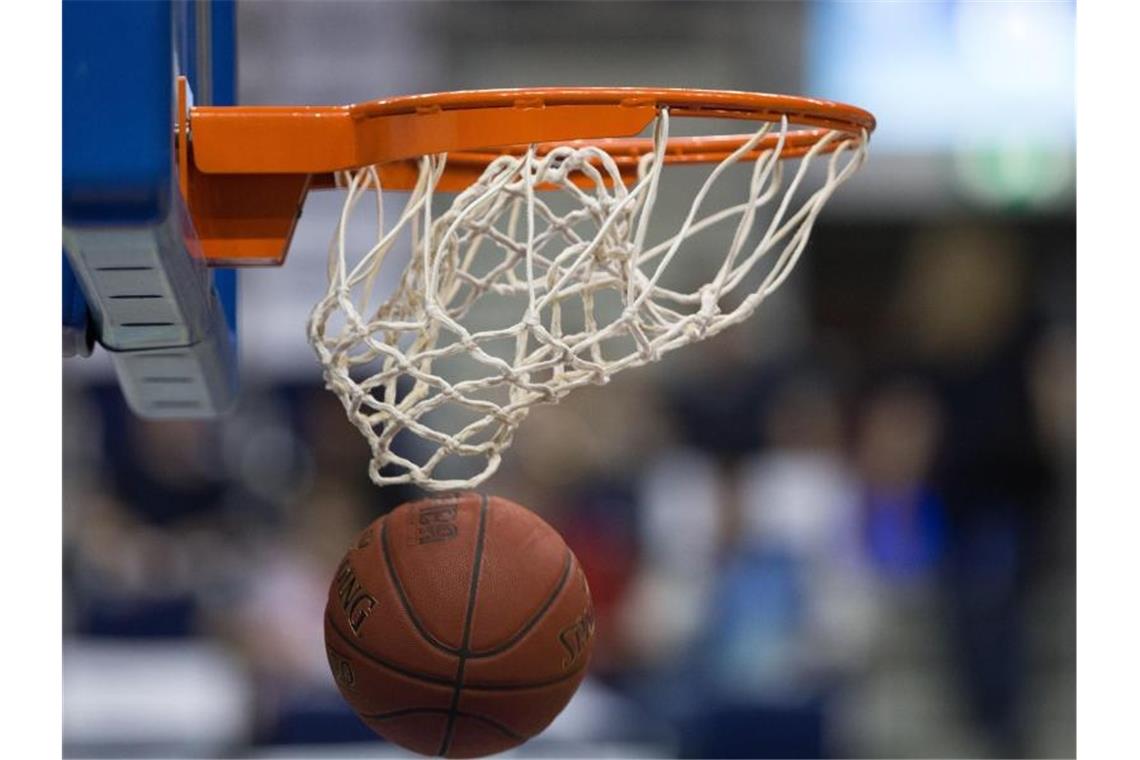 Ein Basketball fällt durch das Netz vom Basketballkorb. Foto: Lukas Schulze/dpa/Symbolbild