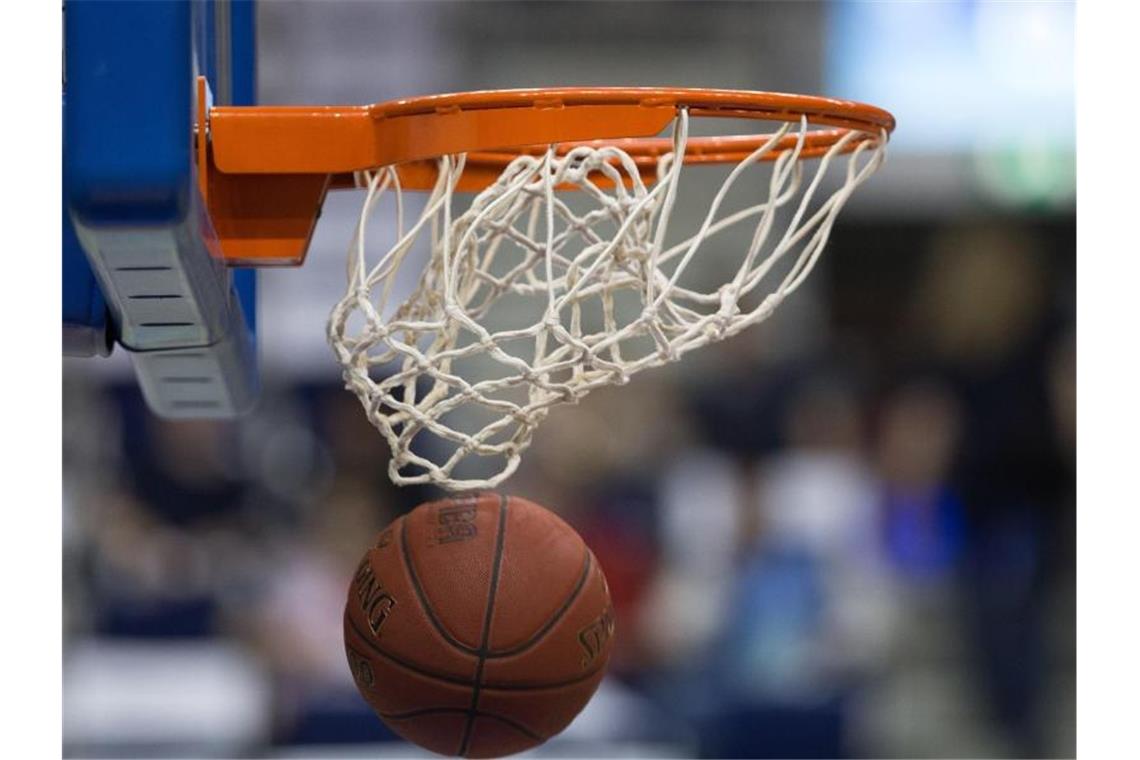 Ein Basketball fällt durch das Netz vom Basketballkorb. Foto: Lukas Schulze/dpa/Archivbild