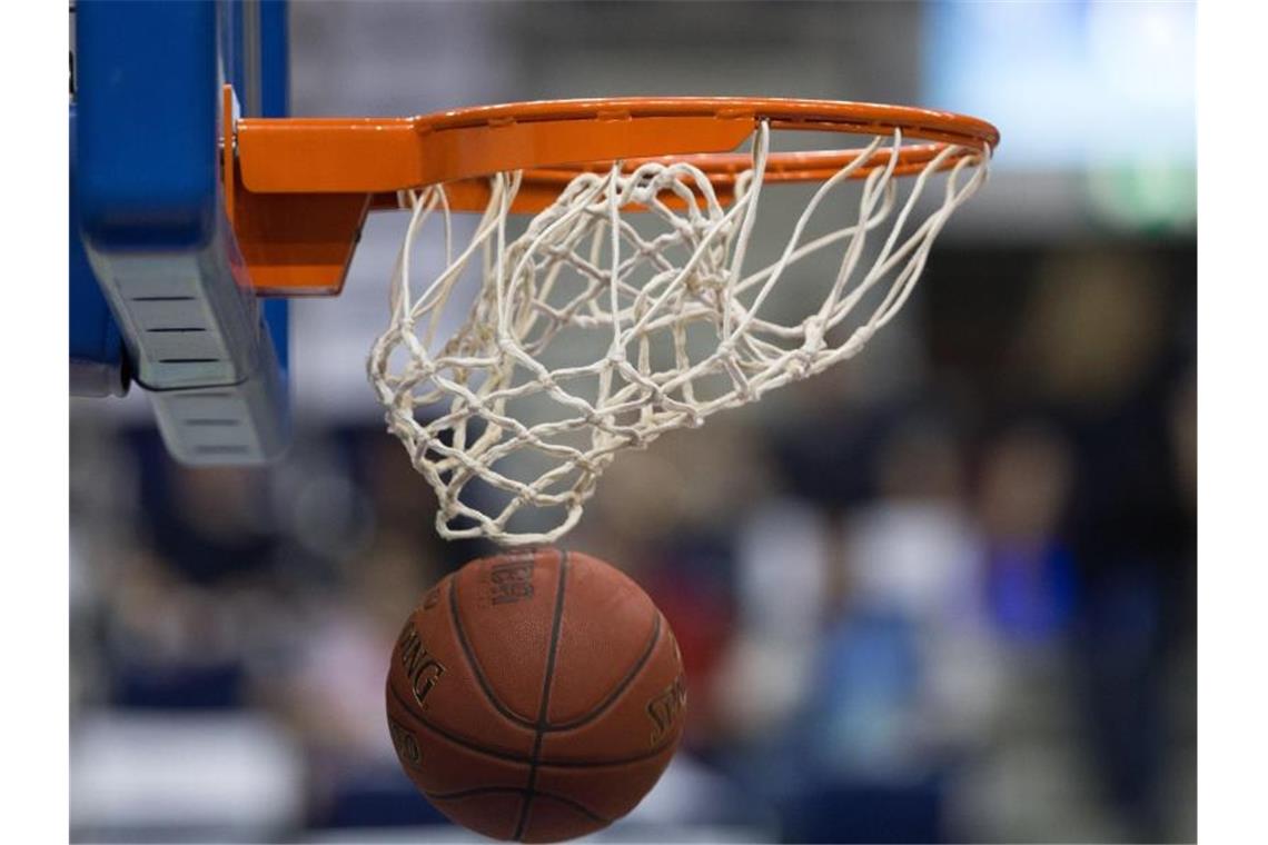 Ein Basketball fällt durch das Netz vom Basketballkorb. Foto: Lukas Schulze/Archiv