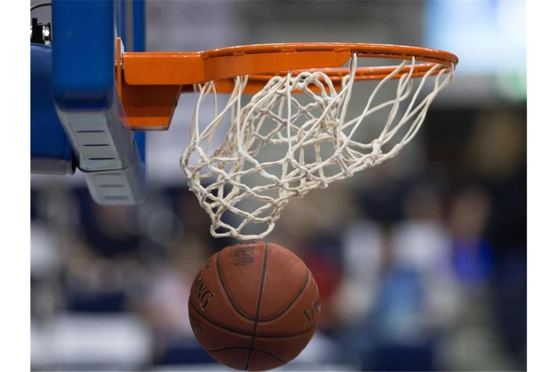 Ein Basketball fällt durch das Netz vom Basketballkorb. Foto: Lukas Schulze/dpa/Archiv/Symbolbild