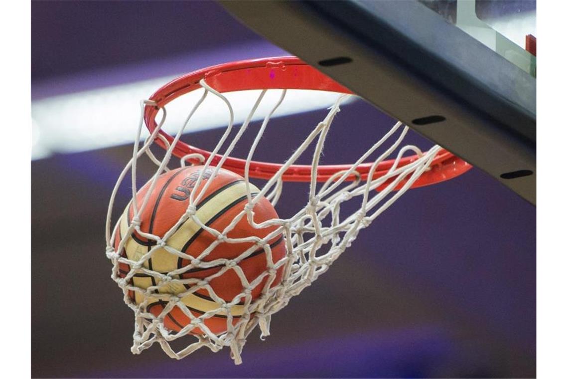 Ein Basketball fällt in den Basketballkorb. Foto: Lukas Schulze/dpa