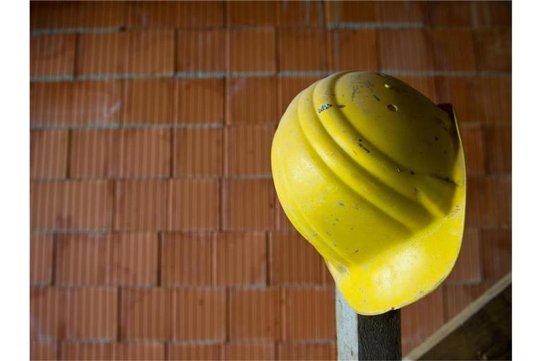 Ein Bauhelm hängt auf einer Baustelle. Foto: Daniel Bockwoldt/dpa/Symbolbild