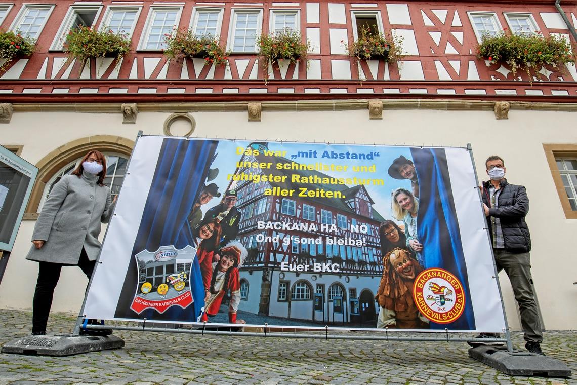Ein Bauzaun mit einem Plakat ist in diesem Jahr das einzige Zeichen für den Beginn der neuen Karnevalskampagne. BKC-Präsidentin Gabi Kallfaß und der Ordensratsvorsitzende, „Nachtwächter“ Horst Klöpfer, platzierten den Hingucker gestern vor dem Backnanger Rathaus. Foto: A. Becher