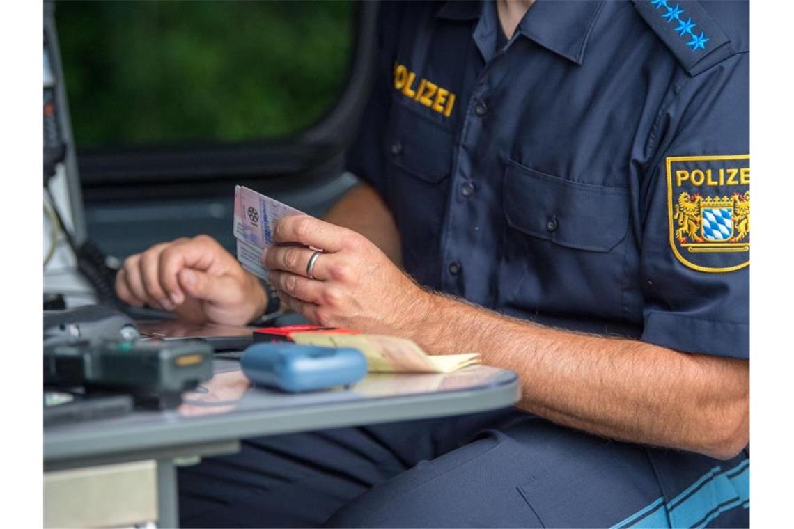 Ein Beamter der bayerischen Grenzpolizei kontrolliert am Grenzübergang Kirchdorf Dokumente von Autofahrern. Foto: Lino Mirgeler/dpa/Archiv