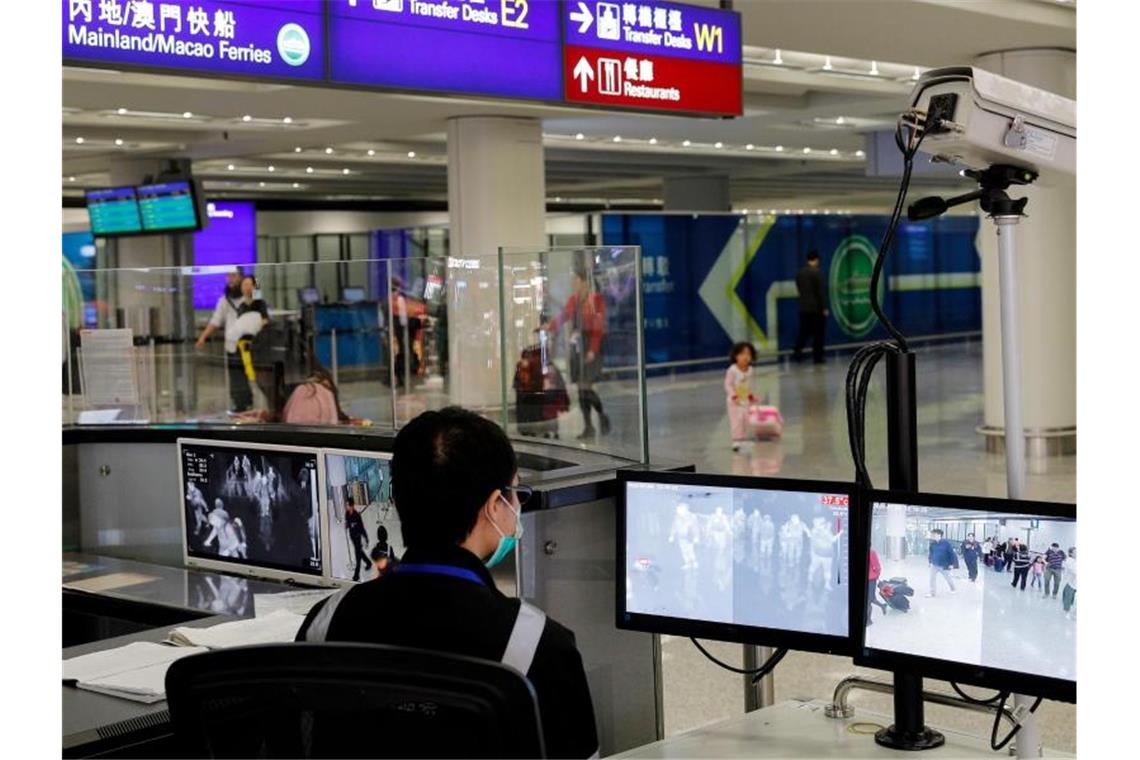 Ein Beamter der Gesundheitsüberwachung überwacht am Flughafen von Hongkong mit Wärmebildkameras die Temperatur von Reisenden. Foto: Andy Wong/AP/dpa