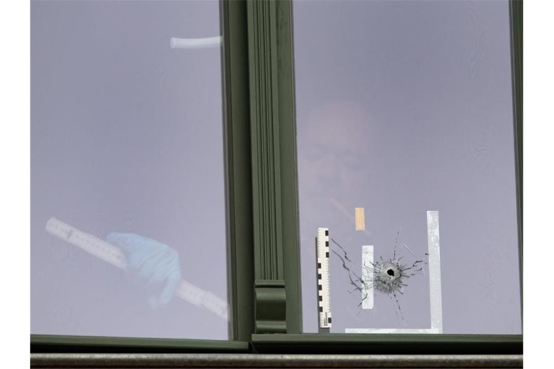 Terroranschlag von Halle: Attentäter legt Geständnis ab Ein Beamter der Spurensicherung untersucht das Loch in einem Fenster in einem Haus gegenüber der Synagoge. Foto: Soeren Stache/dpa-Zentralbild/dpa