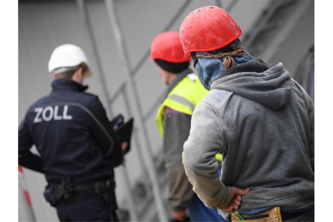 Ein Beamter des Zoll kontrolliert Bauarbeiter. Foto: Arne Dedert/Archiv