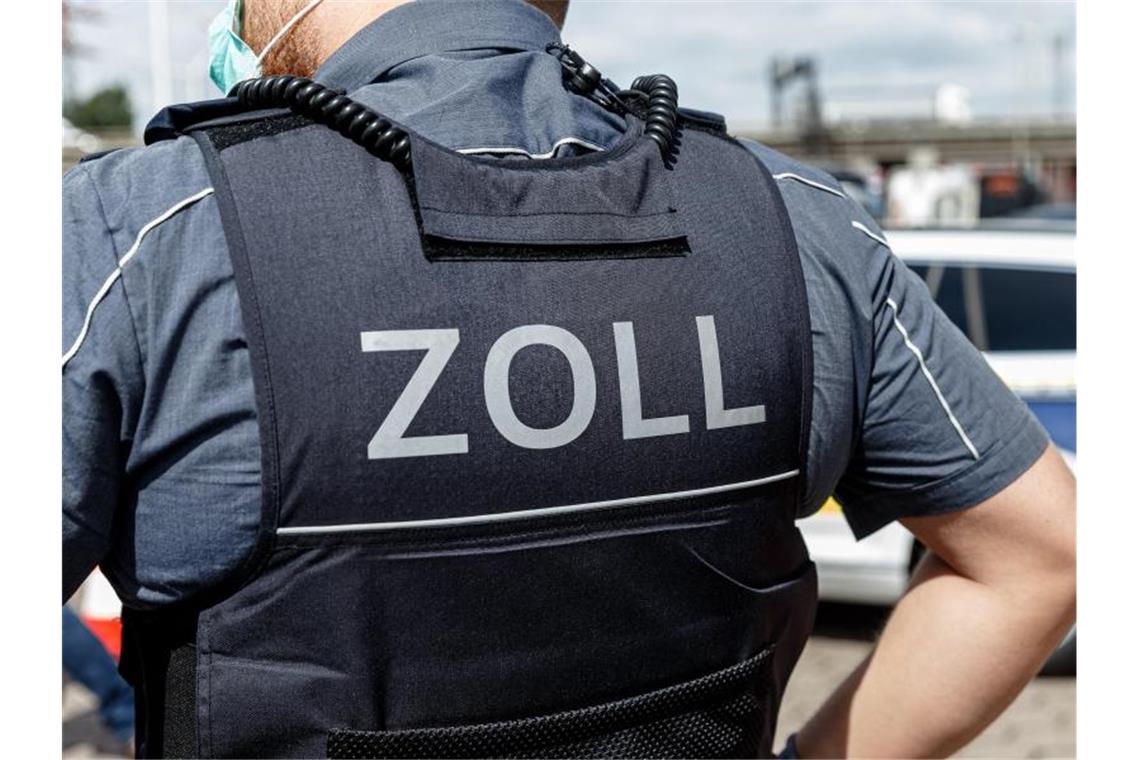 Ein Beamter trägt während seines Dienstes eine Schutzweste mit der Rückenaufschrift „Zoll“. Foto: Markus Scholz/dpa/Symbolbild