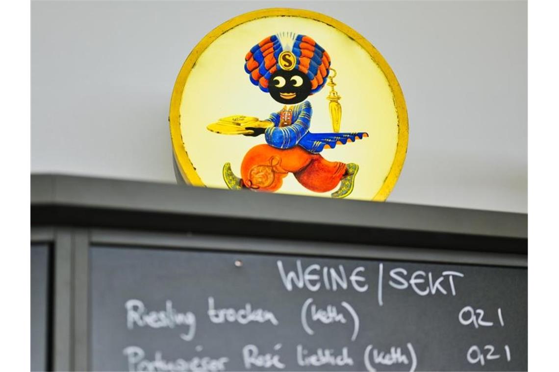 Umgestaltete „Sarotti-Mohr“-Werbung wird erstmals gezeigt Ein beleuchtetes Werbeschild mit der Abbildung eines sogenannten „Sarotti-Mohr“ steht auf der Preistafel. Foto: Uwe Anspach/dpa