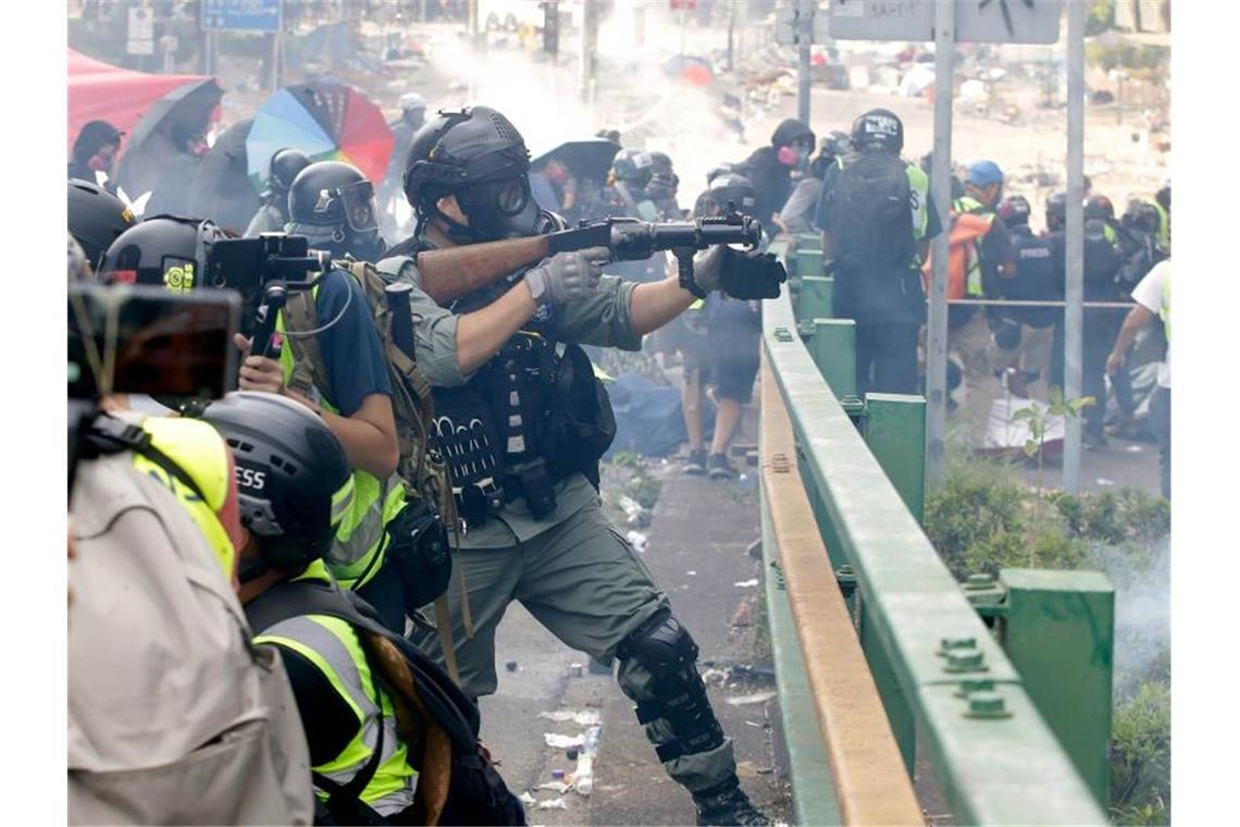 Blamage für Hongkonger Regierung: Vermummungsverbot gekippt Ein Bereitschaftspolizist legt sein Gewehr an, um Tränengas abzufeuern. Foto: Achmad Ibrahim/AP/dpa