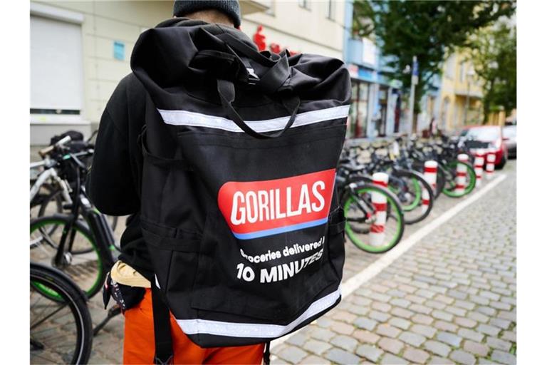 Ein Beschäftigter des Lieferdienstes Gorillas trägt einen Rucksack und steht vor den Fahrrädern. Foto: Annette Riedl/dpa/Archiv