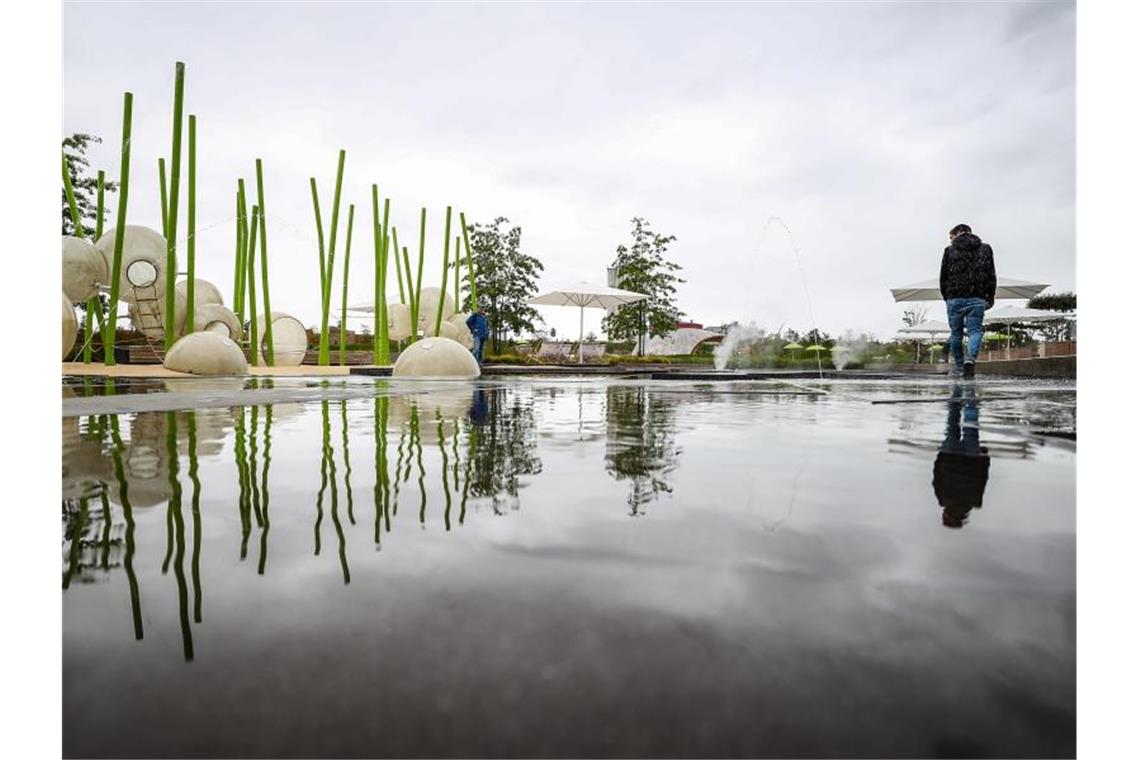 Ein Besucher geht auf dem Gelände der Bundesgartenschau in Heilbronn über den Wasserspielplatz. Foto: Christoph Schmidt/dpa