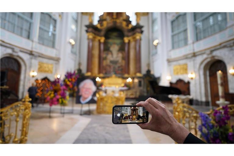 Ein Besucher macht zu Beginn der Trauerfeier ein Foto mit einem Smartphone.