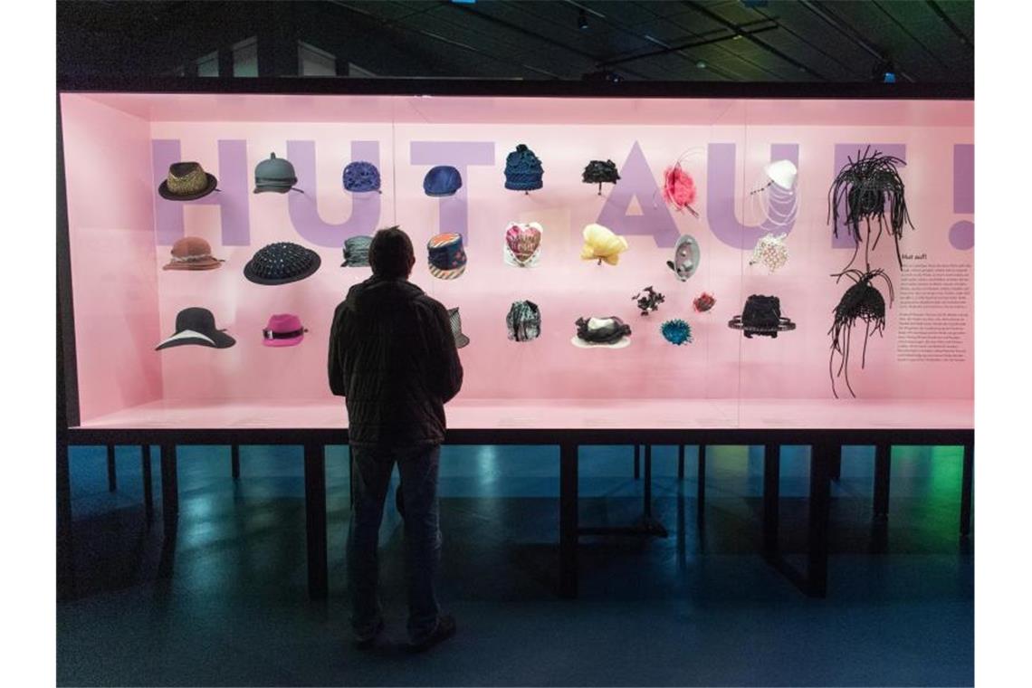 Ein Besucher steht vor einer Vitrine mit Mützen bei der Ausstellung „Hut ab!“ im Haus der Geschichte. Foto: Tom Weller/dpa