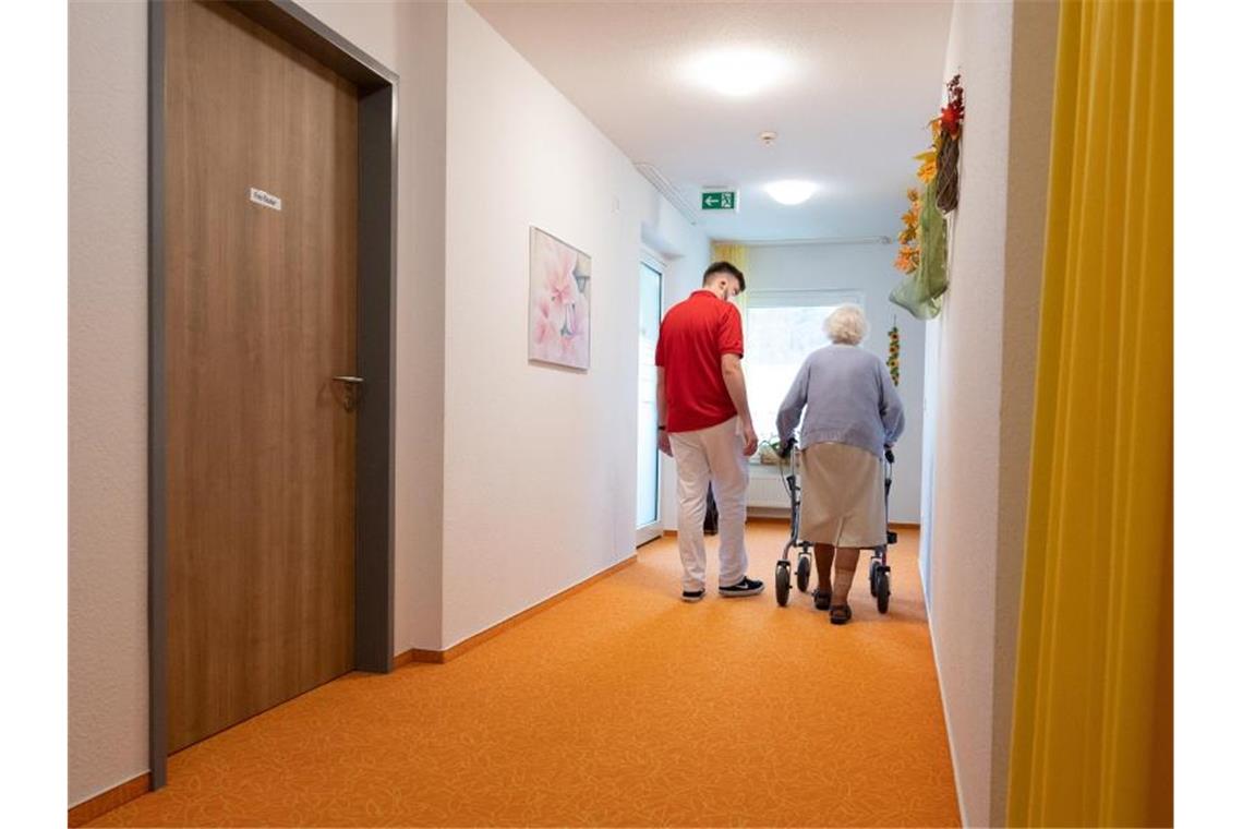 Fast jeder zweite Bewohner in Pflegeheim coronainfiziert Ein Betreuer läuft einem Pflegeheim mit einer Bewohnerin auf einem Flur. Foto: Bernd Weißbrod/dpa/Symbolbild