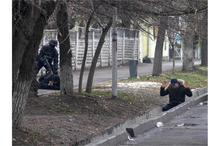 Ein bewaffneter Bereitschaftspolizist im kasachischen Almaty hält während einer sogenannten Anti-Terror-Operation zwei Demonstranten fest. Foto: Vasily Krestyaninov/AP/dpa