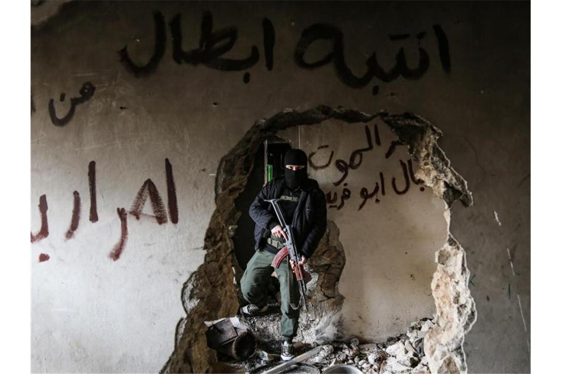 Ein bewaffneter Kämpfer der Miliz Haiat Tahrir al-Scham inspiziert ein beschädigtes Haus. Foto: Anas Alkharboutli/dpa/Archiv