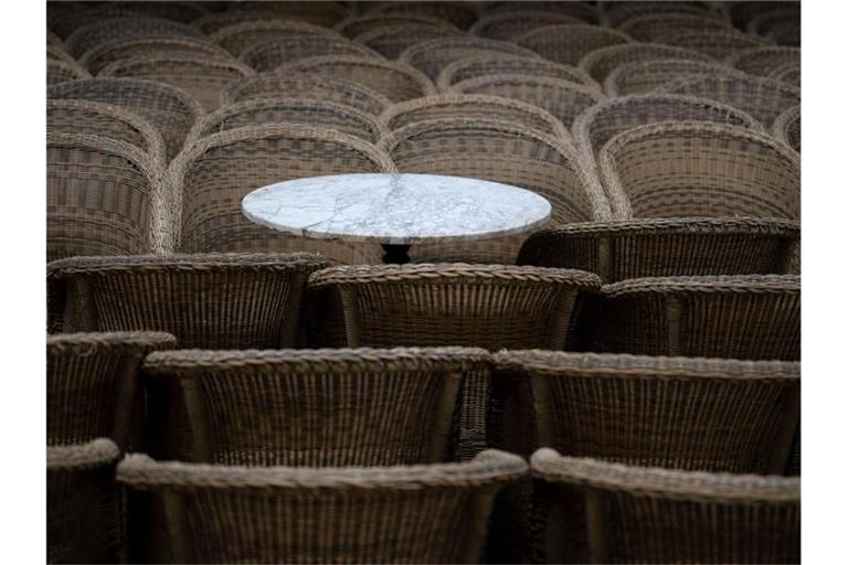 Ein Bistrotisch steht im Außenbereich eines gastronomischen Betriebs zwischen Stühlen. Foto: Marijan Murat/dpa/Symbolbild