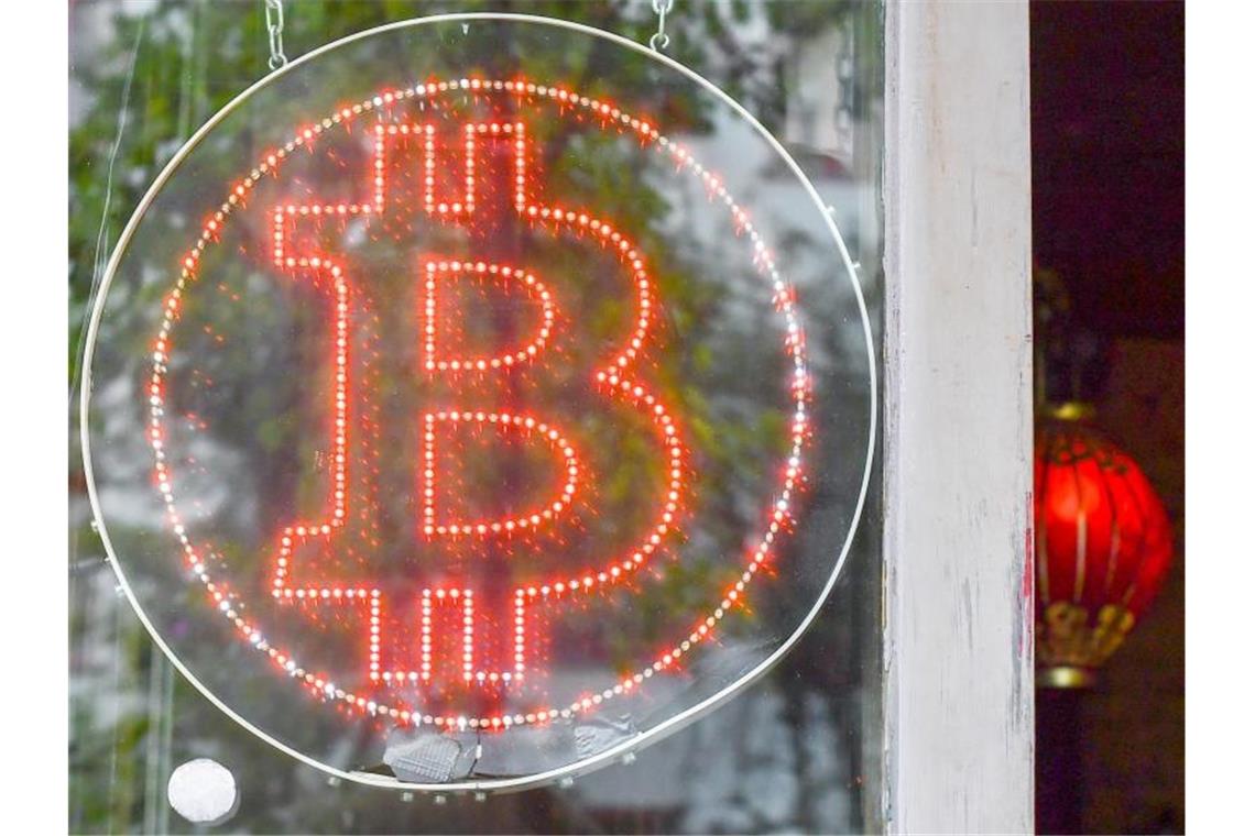 Ein Bitcoin-Logo in einem Schaufenster einer Kneipe im Kreuzberger Graefekiez. Foto: Jens Kalaene/ZB/dpa