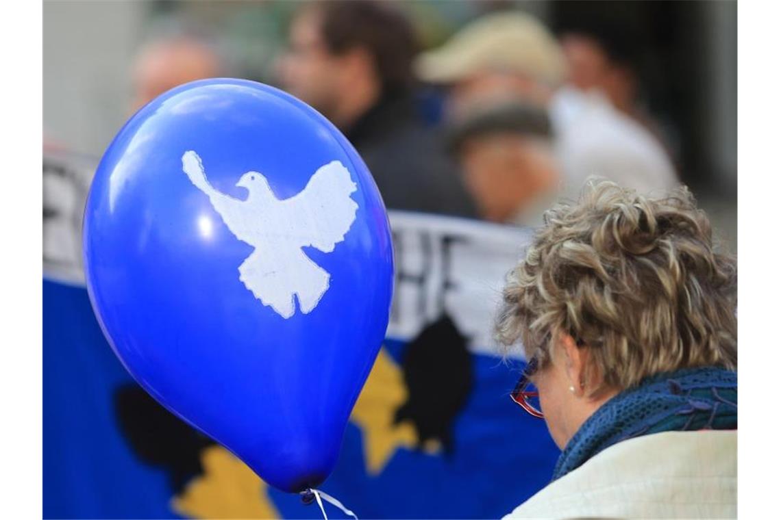 Ein blauer Luftballon mit dem Symbol einer weißen Friedenstaube. Foto: Jens Wolf/Archivbild