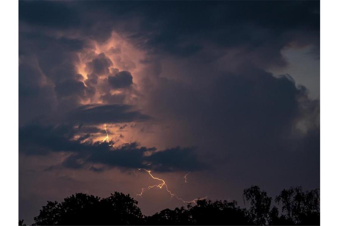 Ein Blitz hellt hinter dunklen Wolken auf. Foto: Fabian Sommer/dpa/Symbolbild