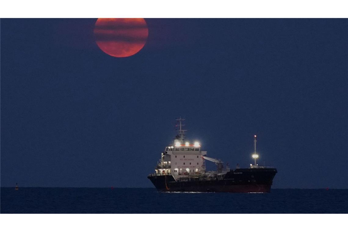 Ein Blutmond geht über dem Mittelmeer bei Limassol auf, wo ein Schiff vor Anker liegt.