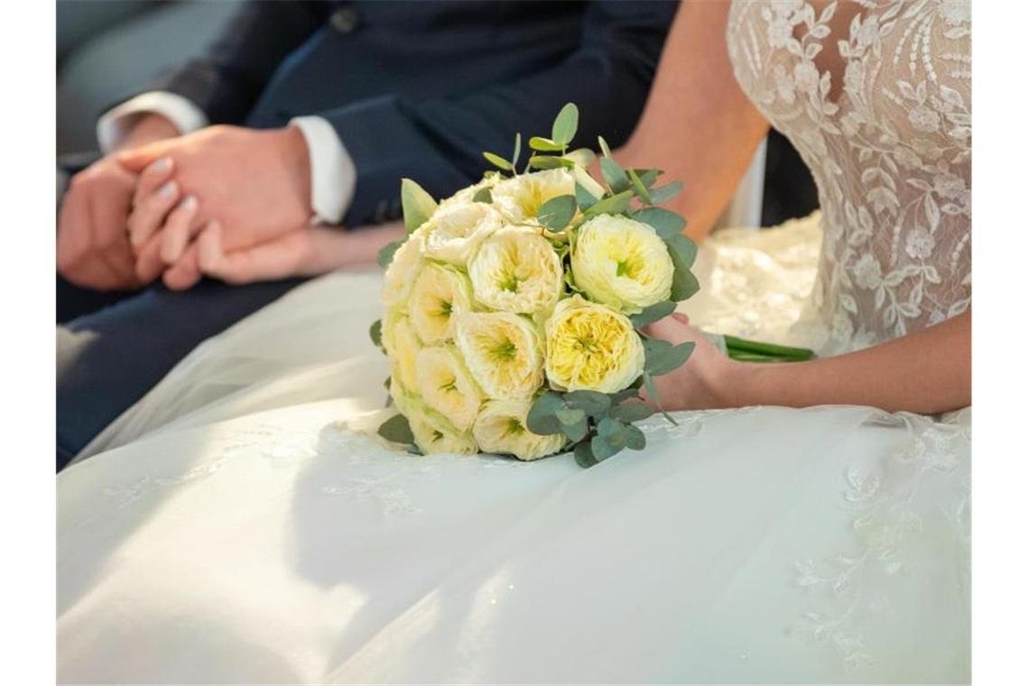 Pferde stürmen ohne Hochzeitspaar los Ein Brautpaar hält sich während ihrer Trauung die Hände. Foto: Silas Stein/dpa/Illustration