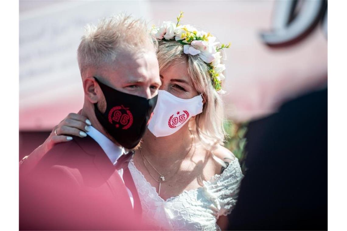 Ein Brautpaar steht mit Mundschutz bei seiner Trauung im Autokino. Foto: Fabian Strauch/dpa/Archivbild