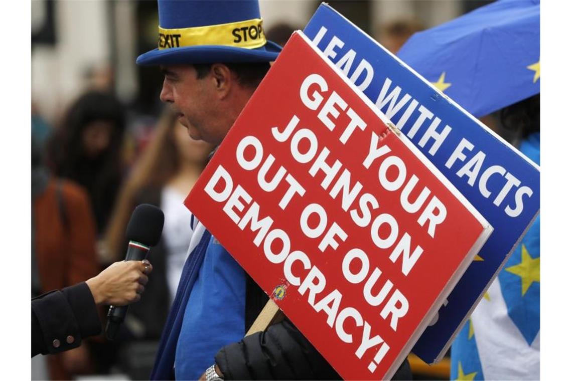 Ein Brexit-Gegner spricht vor dem Parlament zu Journalisten und hält ein Schild mit der Aufschrift „Get your Johnson out of our democracy“ (Entfernt euren Johnson aus unserer Demokratie). Foto: Frank Augstein/AP
