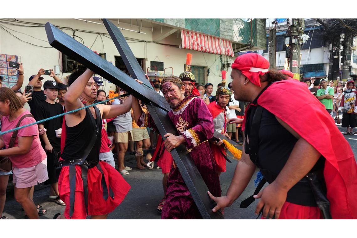 Ein Büßer mit einem Holzkreuz während eines Passionsspiels in Mandaluyong, das die Leiden Jesu Christi nachstellt. Die Szene spielt am Gründonnerstag im Rahmen der Karwochen-Feierlichkeiten.