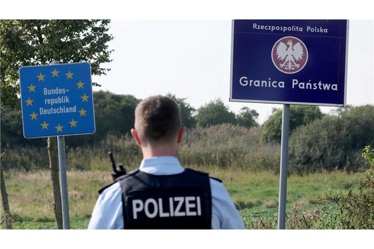 Ein Bundespolizist steht vor den Schildern für Deutschland und Polen. Als Reaktion auf die deutschen Kontrollen will nun auch Polen an der Grenze kontrollieren. (Archivbild)