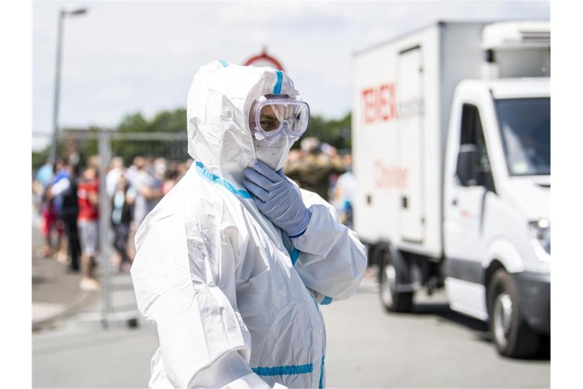 Ein Bundeswehr-Soldat im Schutzanzug und mit Mund-Nasenschutzmaske in Verl. Dort stehen mehrere Mehrfamilienhäuser, in denen Werkvertragsarbeiter der Firma Tönnies leben, unter Quarantäne. Foto: David Inderlied/dpa