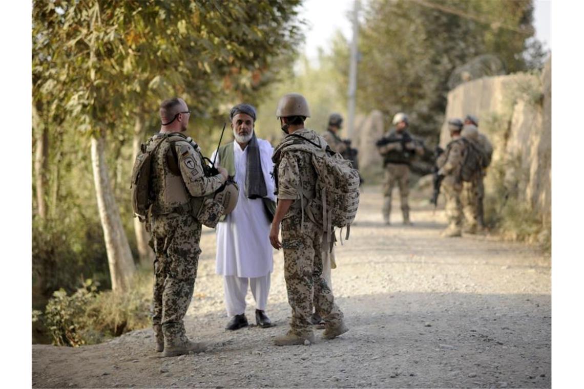 Ein Bundeswehrsoldat (l) und ein Dolmetscher (r) sprechen nahe Kundus im Distrikt von Char Darreh mit einem Mann. Foto: Maurizio Gambarini/dpa