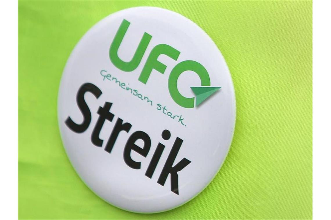 Gewerkschaft Ufo weitet Warnstreik aus Ein Button der Flugbegleitergewerkschaft UFO ist auf hellgrünem Hintergrund zu sehen. Foto: Oliver Berg/dpa/Archivbild