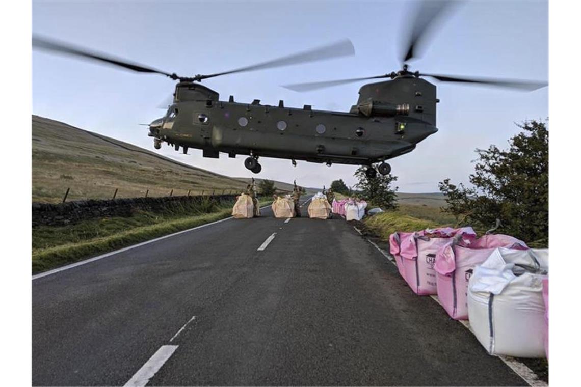 Ein „Chinook“-Lasten-Hubschrauber ist im Einsatz, um mit Sand-Kies-Säcken die Mauer des Reservoirs zu stabilisieren und an anderer Stelle Wasserläufe umzuleiten. Foto: Raf Benson/MOD/AP