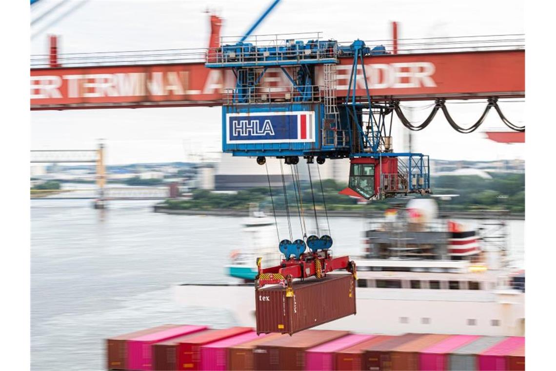 Ein Container wird auf dem Container Terminal Altenwerder im Hamburger Hafen mit einer Containerbrücke auf ein Schiff geladen. Nur in kleinen Schritten kommt Deutschlands Exportwirtschaft aus dem Corona-Tief. Foto: Daniel Reinhardt/dpa