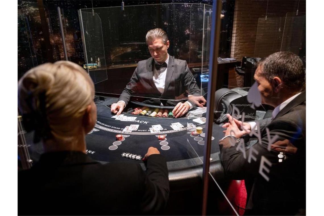 Coronakrise setzt Spielbanken stark zu Ein Croupier (M) gibt in der Spielbank Stuttgart an einem Black-Jack-Tisch Karten aus. Foto: Marijan Murat/dpa/Illustration/Archiv