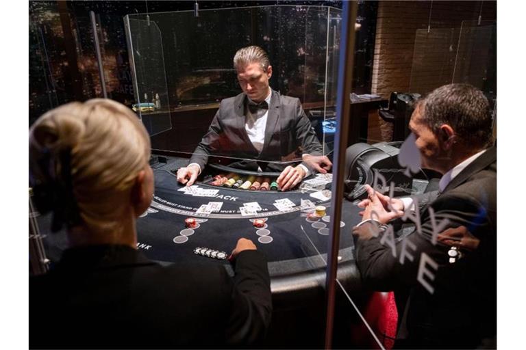 Ein Croupier (M) gibt in der Spielbank Stuttgart an einem Black Jack Tisch Karten aus. Foto: Marijan Murat/dpa/Illustration