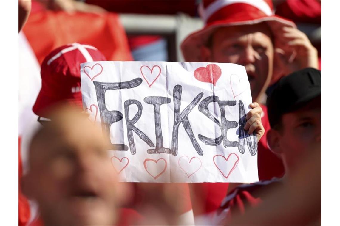 Ein dänischer Fan hält ein Plakat für Eriksen in die Höhe. Foto: Friedemann Vogel/EPA Pool/AP/dpa